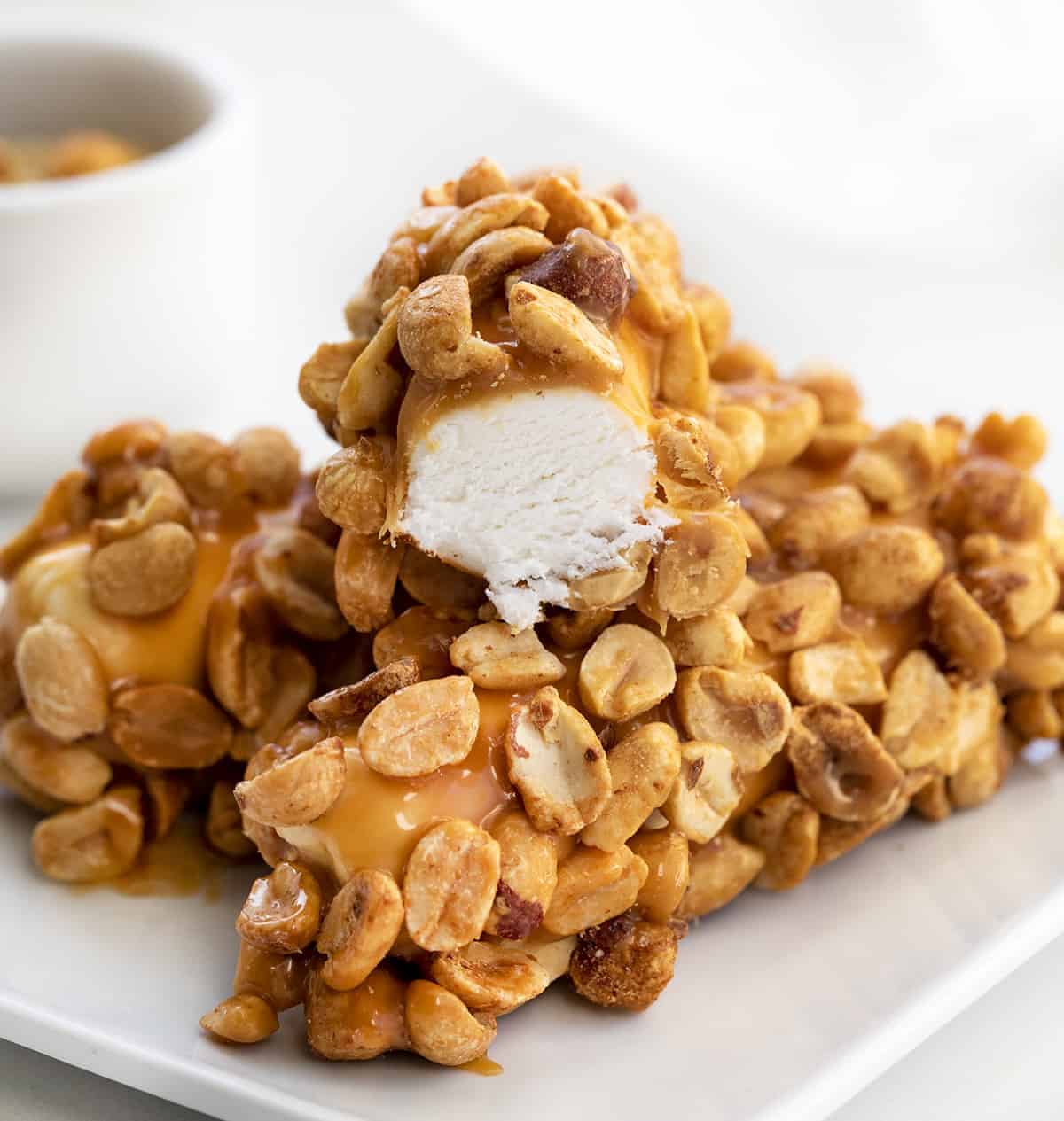 Homemade Salted Caramel Nut Rolls are made with a fluffy marshmallow nougat coated in caramel and rolled in salted peanuts. Nut Roll Candybar, How to Make A Nutroll, Nut Roll Recipes, Original Nut Roll, Homemade Candy Bar, Candy, dessert, recipes, Christmas, New Years, Valentines Day, I am baker, iambaker 咸焦糖螺母卷放在一个白盘子里