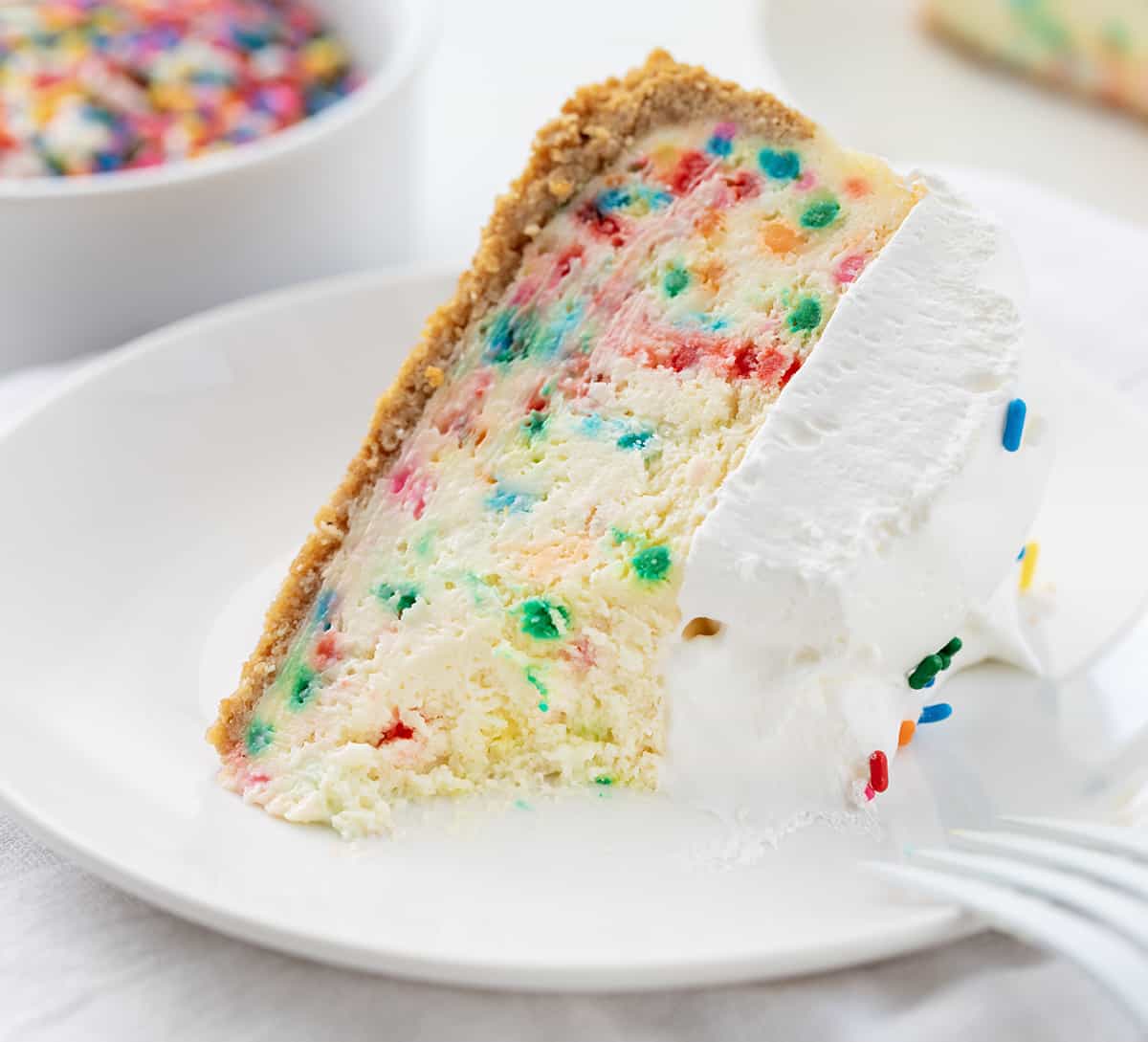 生日块芝士蛋糕在白色板铺设与咬边,白色的叉放在盘子里。