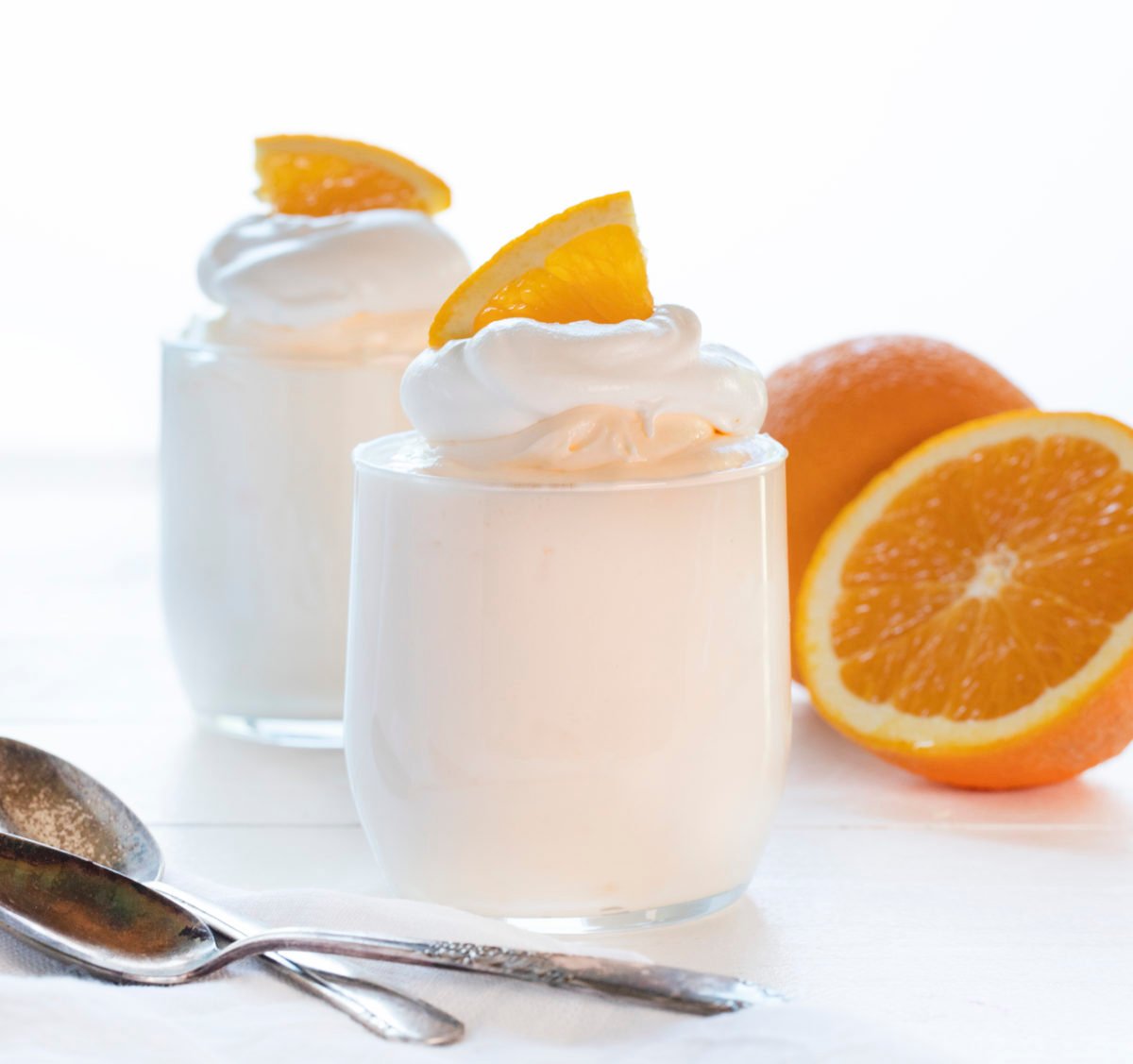 橙色Creamsicle慕斯杯橘子在背景和勺子在前面。