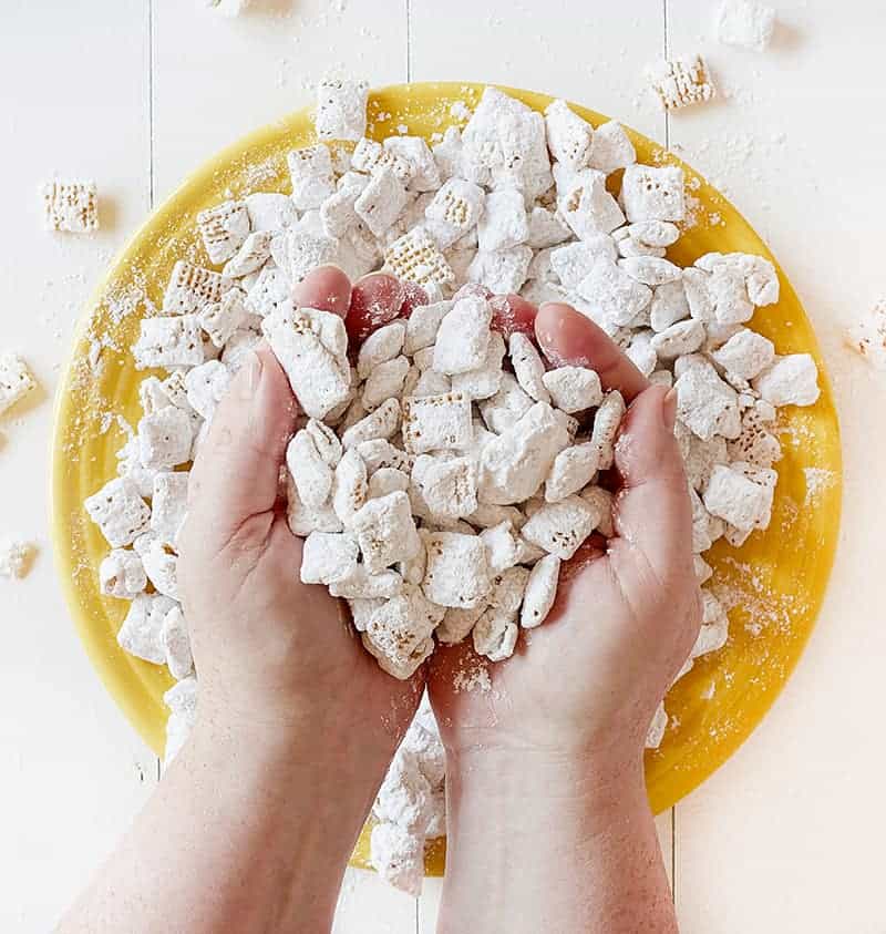 Banana Pudding Puppy Chow--a banana flavored twist to the classic puppy chow (muddy buddies) recipe #bananapuddingpuppychow #muddybuddies #bananapuddingmix #chexcereal #almondbark #ricechex #iambaker 手里满是香蕉布丁小狗粮