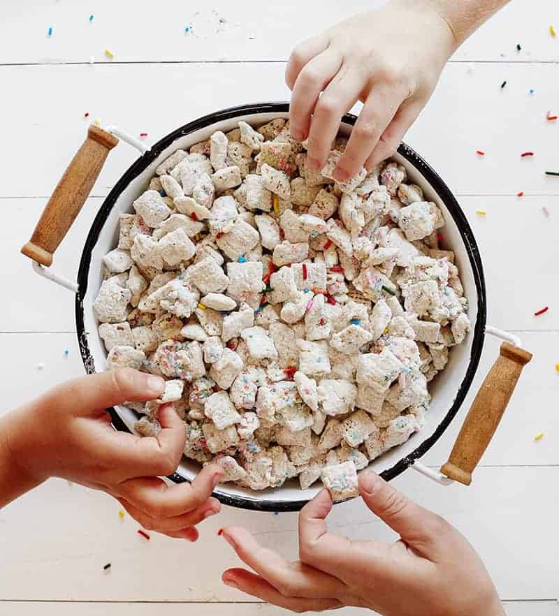 This Birthday Cake Puppy Chow tastes exactly like cake! Just four simple ingredients and you have an easy snack the kids will beg you for! #puppychow #muddiebuddies #birthdaycakepuppychow #birthdaycakemuddiebuddies #funfettipuppychow #sprinklespuppychow #funfettimuddiebuddies #snack #easysnacks #iambaker 孩子们的手抓生日蛋糕小狗饲料在碗里
