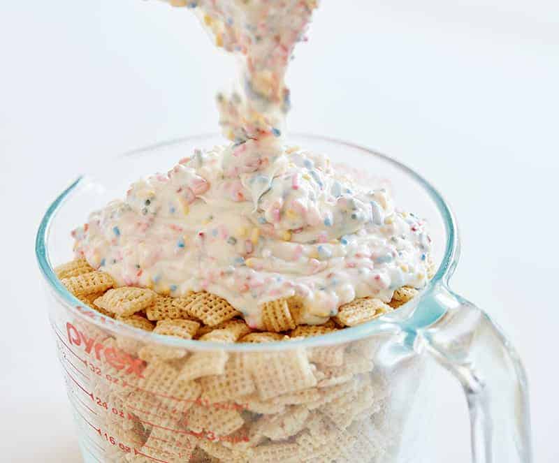 This Birthday Cake Puppy Chow tastes exactly like cake! Just four simple ingredients and you have an easy snack the kids will beg you for! #puppychow #muddiebuddies #birthdaycakepuppychow #birthdaycakemuddiebuddies #funfettipuppychow #sprinklespuppychow #funfettimuddiebuddies #snack #easysnacks #iambaker 彩虹巧克力生日蛋糕小狗餐食谱