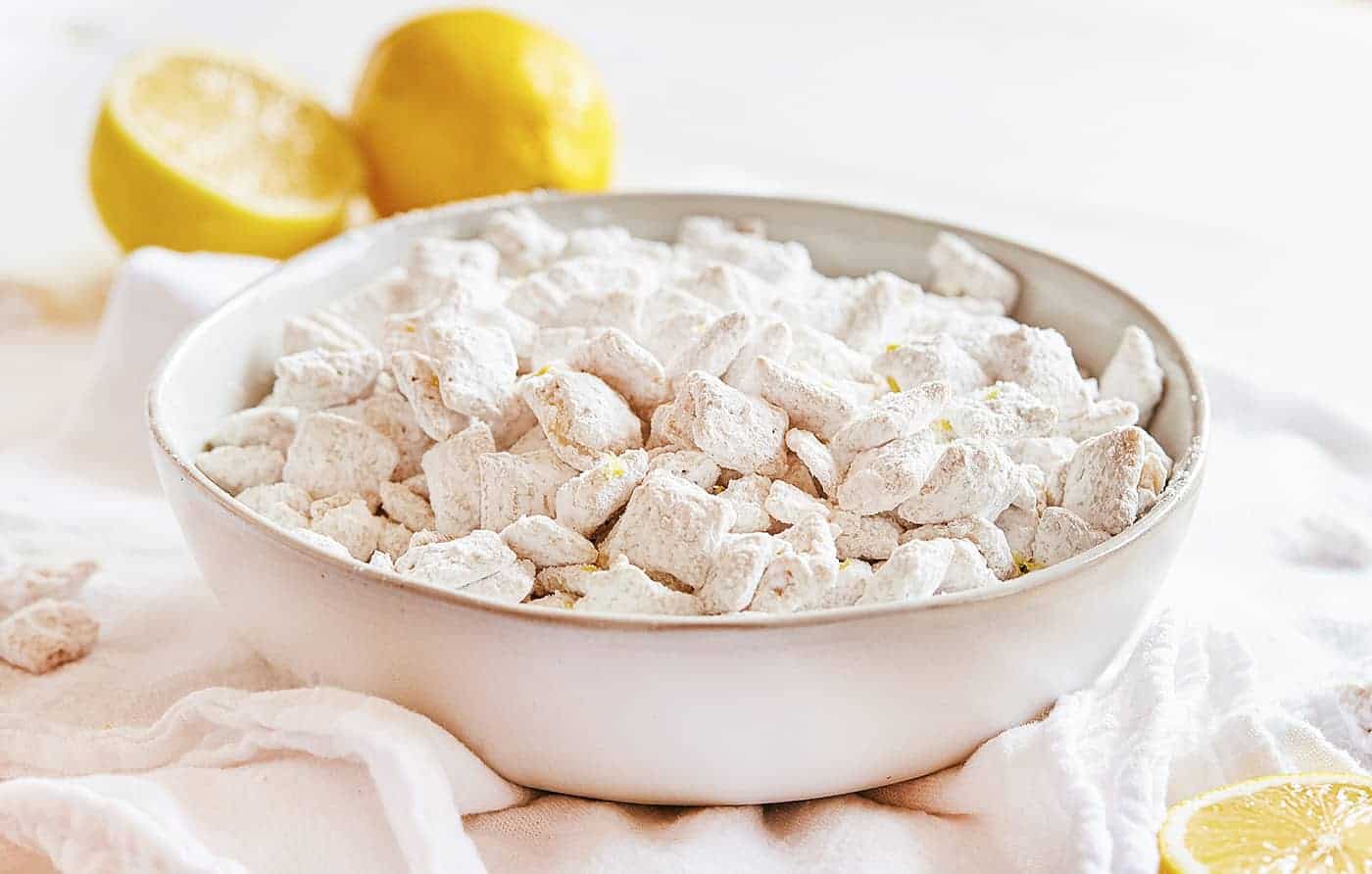 Lemon Puppy Chow (aka Muddie Buddies) is a super fun citrus twist on a classic! Sweet vanilla and lemon flavor all wrapped up in an easy-to-eat snack! #lemonpuppychow #lemonmuddiebuddies #puppychow #puppychowrecipe #muddiebuddies #easysnacks #snacks #afterschool #iambaker #nobake 柠檬泥弟食谱