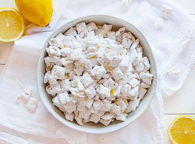 Lemon Puppy Chow (aka Muddie Buddies) is a super fun citrus twist on a classic! Sweet vanilla and lemon flavor all wrapped up in an easy-to-eat snack! #lemonpuppychow #lemonmuddiebuddies #puppychow #puppychowrecipe #muddiebuddies #easysnacks #snacks #afterschool #iambaker #nobake 一碗柠檬狗粮