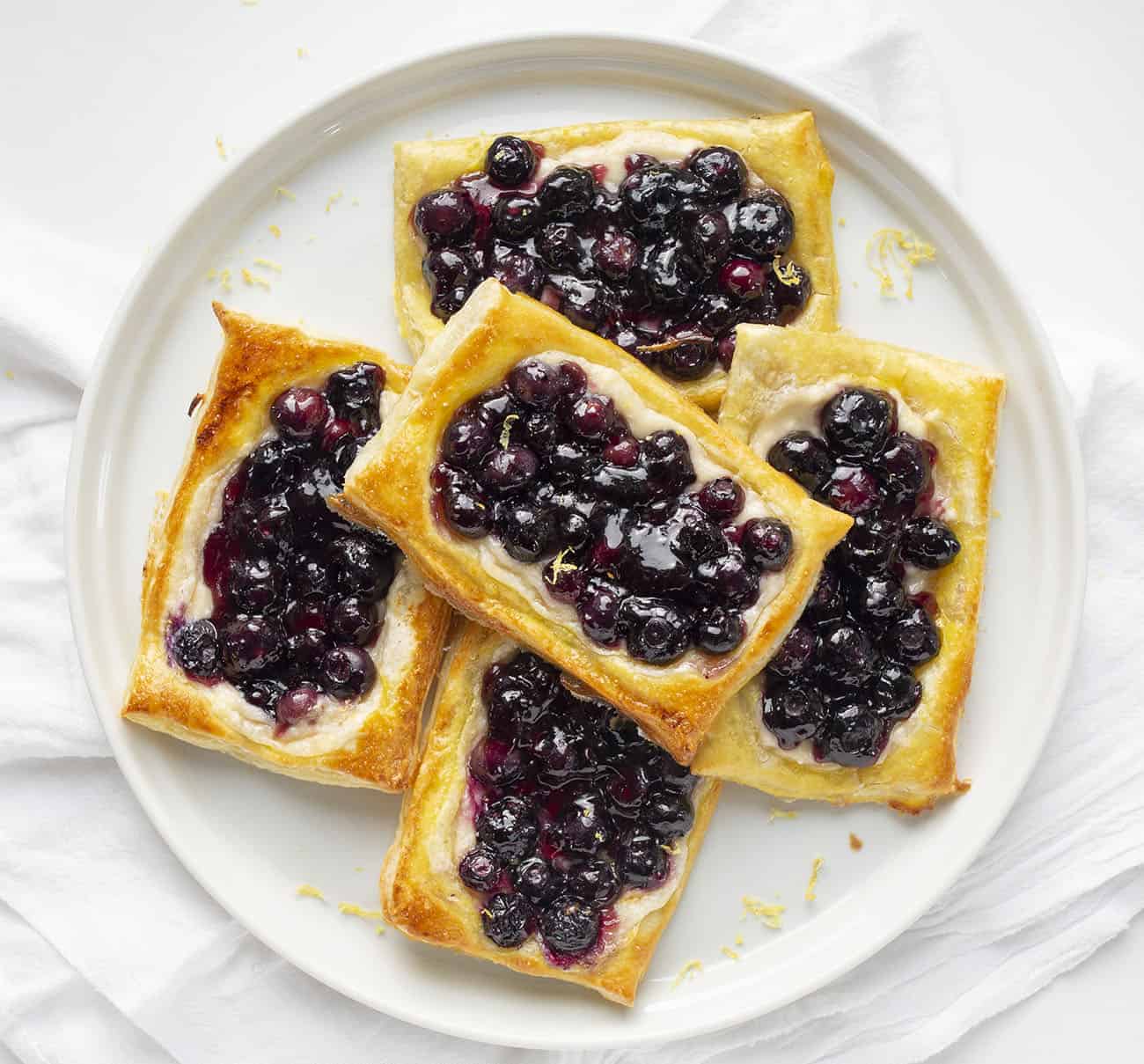 This Lemon Blueberry Danish is a light and fluffy pastry topped with a cream cheese mixture, blueberry jam, and fresh blueberries! Danish, How to Make Danish, Lemon Blueberry Danish, Blueberry Lemon Danish, Breakfast, Breakfast Danish, Lemon Blueberry Pastry, Recipes, i am baker, iambaker 头顶图像柠檬蓝莓丹麦在一个白色盘子