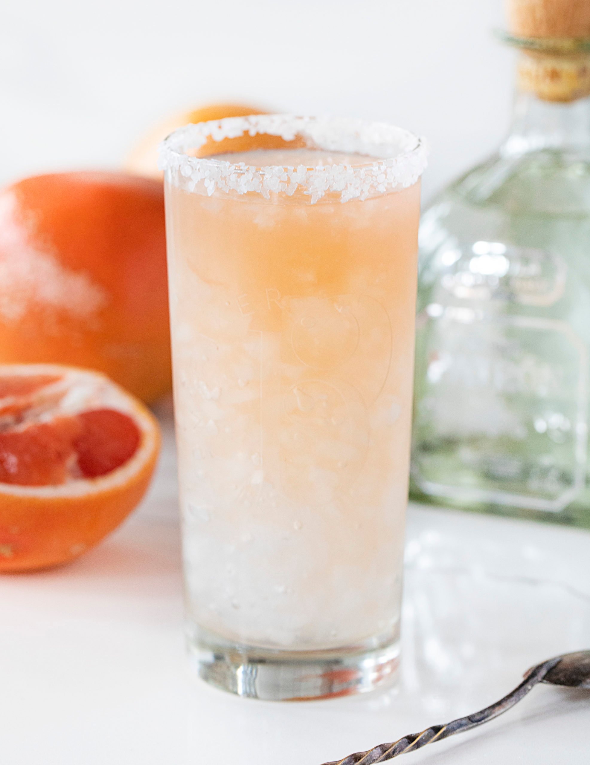 Skip the canned Paloma and make your own grapefruit flavored cocktail with your favorite tequila! Paloma recipe, tequila drinks, tequila, homemade cocktails, iambaker, i am baker 一杯帕洛玛酒,背景是Patron和葡萄柚