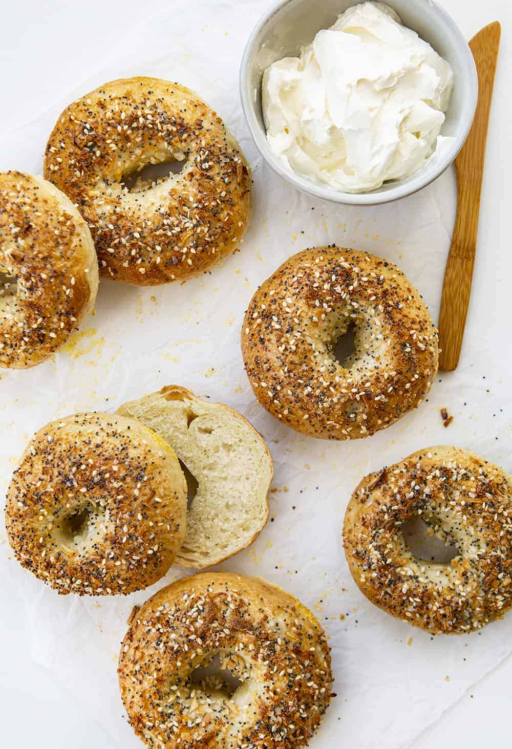 This Everything Bagel takes a plain bagel and tops it with a blend of poppy seeds, sesame seeds, onion flakes, garlic powder, and sea salt! Everything Bagel, How to Make Everything Bagel, Everything Bagel Recipe, Bagels, Bagel Recipes, Homemade Bagels, i am baker, iambaker, baking, breakfast, everything bagel seasoning, recipes 头顶图像的一切百吉饼与奶油奶酪和一个百吉饼切片显示内部
