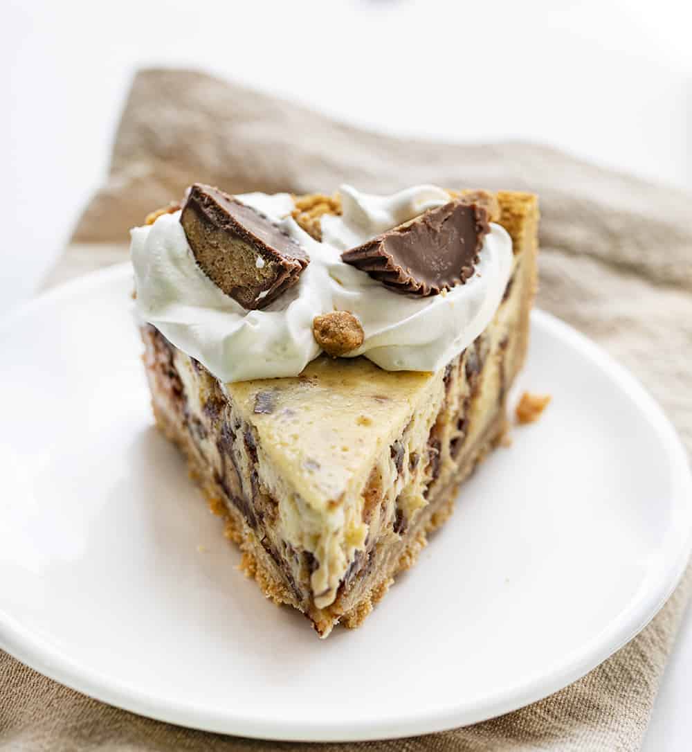 Reese's Cheesecake Pie takes one of my favorite candy treats, Reese's Peanut Butter Cups, and one of my favorite cakes, a cheesecake, and combines the two for this decadent dessert. Cheesecake, Reese's Cheesecake, How to Make Reese's Cheesecake, How to Make Candy Cheesecake, Easy Cheesecake, Summer Baking, Baking, Recipes, Desserts, Easy Desserts, Reese's Peanut Butter Cups, iambaker, i am baker 瑞茜的芝士蛋糕和两块里斯的花生奶油杯上,它看起来像一个愤怒的脸