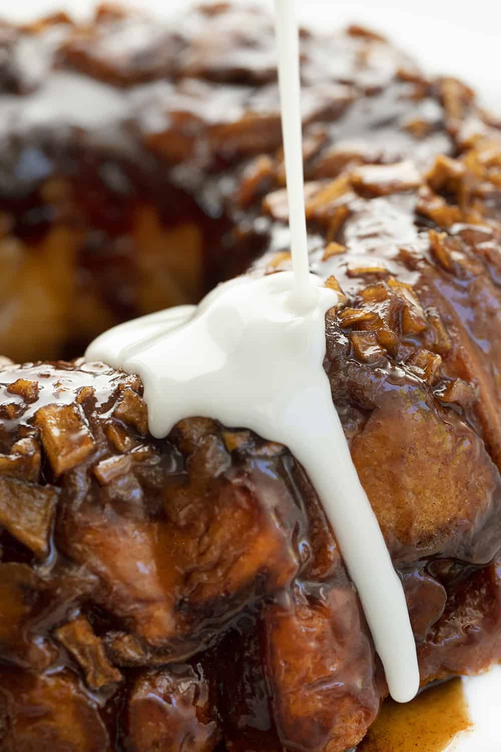 Apple Fritter Monkey Bread is an ooey-gooey pull-apart bread that is filled with chopped apples and covered in a sweet glaze! Monkey Bread, Easy Monkey Bread, Apple Fritters, Apple Fritter Monkey Bread, How to Make Easy Monkey Bread, Apple Fritter Bread, Breakfast, Recipes, Baking, Pillsbury Monkey Bread, i am baker, iambaker 在白拼盘上淋上刚烤好的苹果馅饼猴面包
