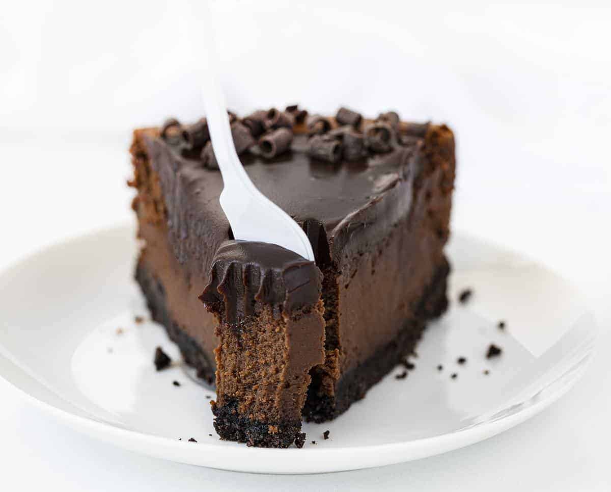 白色叉子从一块巧克力芝士蛋糕上取下一口