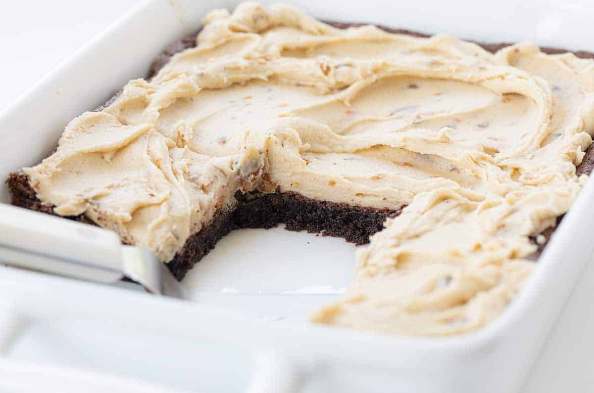 Butterfinger Brownies are fudgy and perfectly baked brownies topped with a sweet homemade Butterfinger frosting! Butterfinger Brownies, Butterfinger Brownie Recipe, Butterfinger Frosting, Butterfinger Buttercream, baking, recipes, iambaker, i am baker, dessert 白平底锅里的奶油手指布朗尼,少了几块