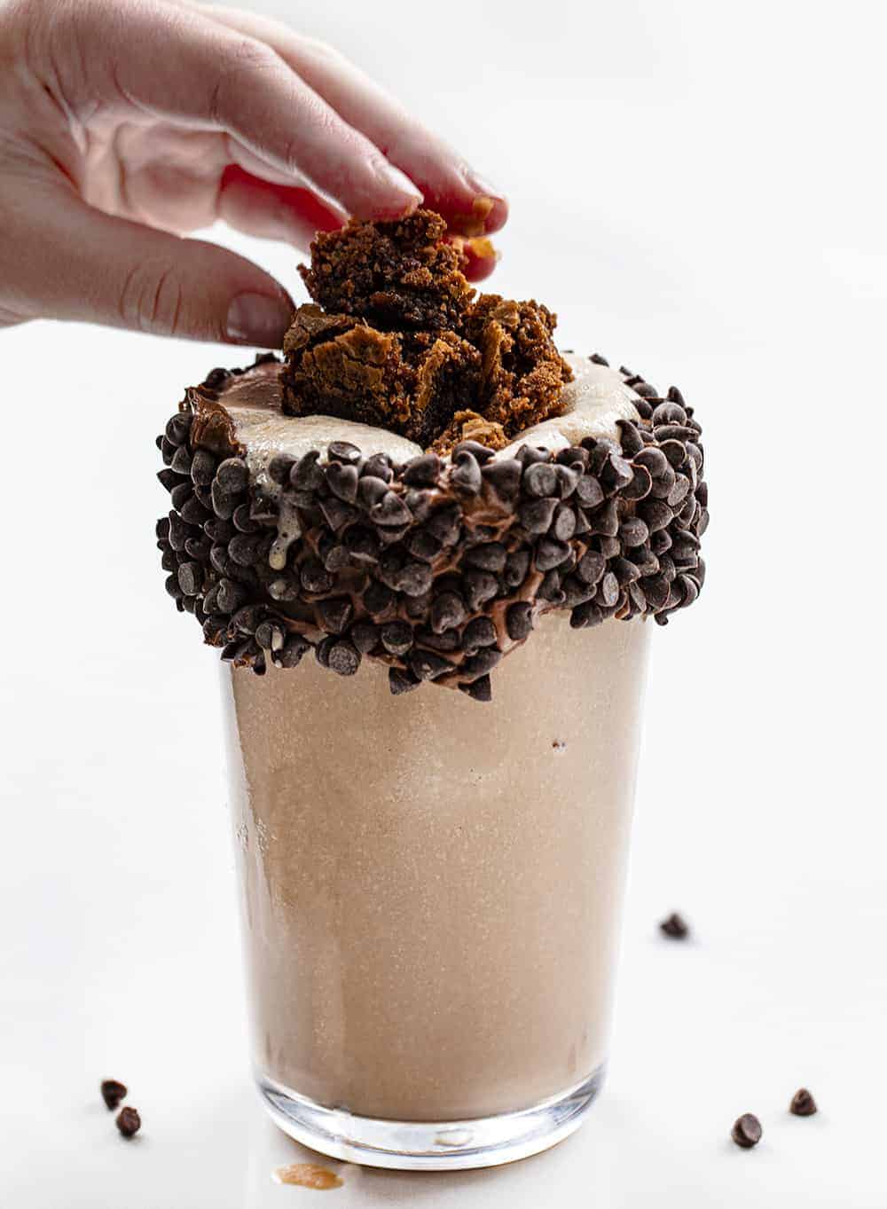 This Chocolate Milkshake is served in a glass with a chocolate frosted rim and mini chocolate chips, all topped with homemade brownie pieces for an extra special milkshake! Chocolate Milkshake, Ultimate Chocolate Milkshake, Brownie Milkshake, Chocolate Milkshake with Brownie, Triple Chocolate Milkshake, milkshake, milkshake recipes, i am baker, iambaker, recipe 手将布朗尼的块添加到玻璃用巧克力奶昔