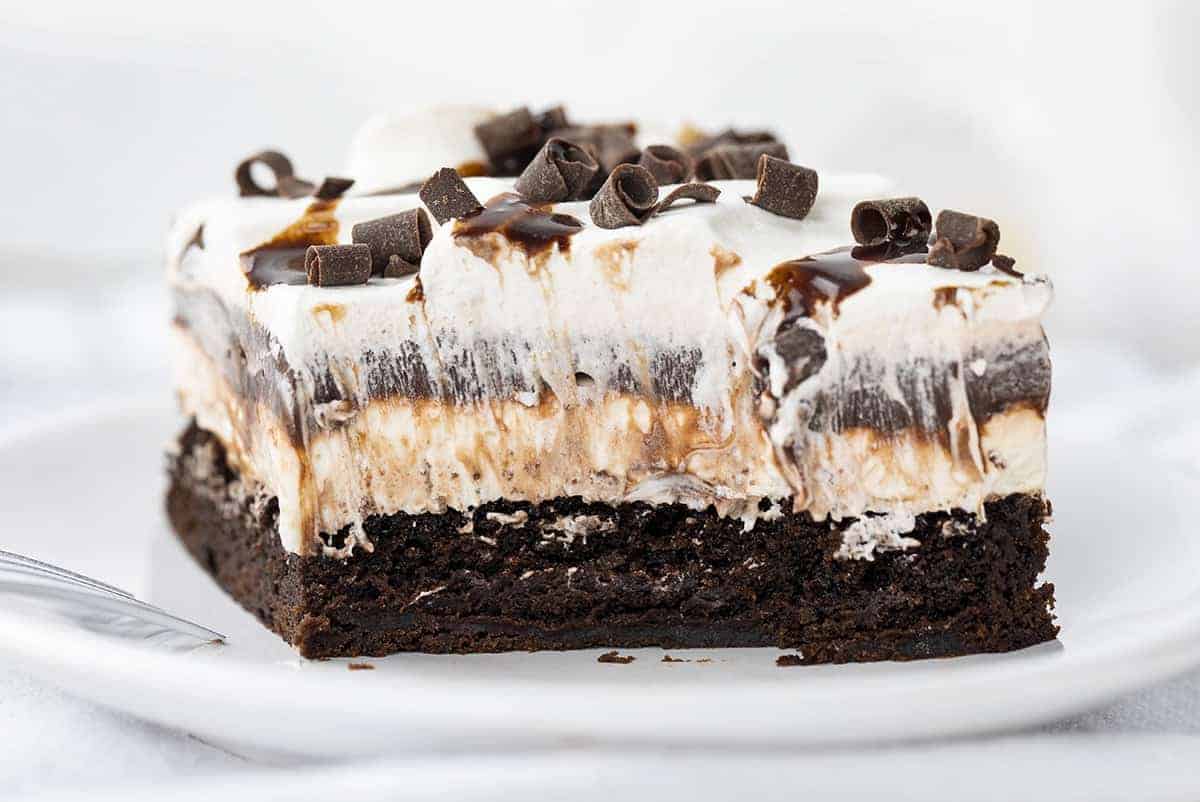 Brownie Pudding Dessert is a decadent layered dessert that starts with the perfect brownie, topped with a cream cheese and chocolate pudding layer, finished off with cool whip and more chocolate! Brownie, Chocolate Pudding, Brownie Pudding Dessert, Brownie Dessert, Dessert, Pudding Dessert, Summer Desserts, Fall Desserts, Winter Dessert, Dessert Recipes, Brownie Recipes, Layered Dessert, i am baker, iambaker 一块巧克力布丁甜点,去掉咬痕,叉子放在盘子上