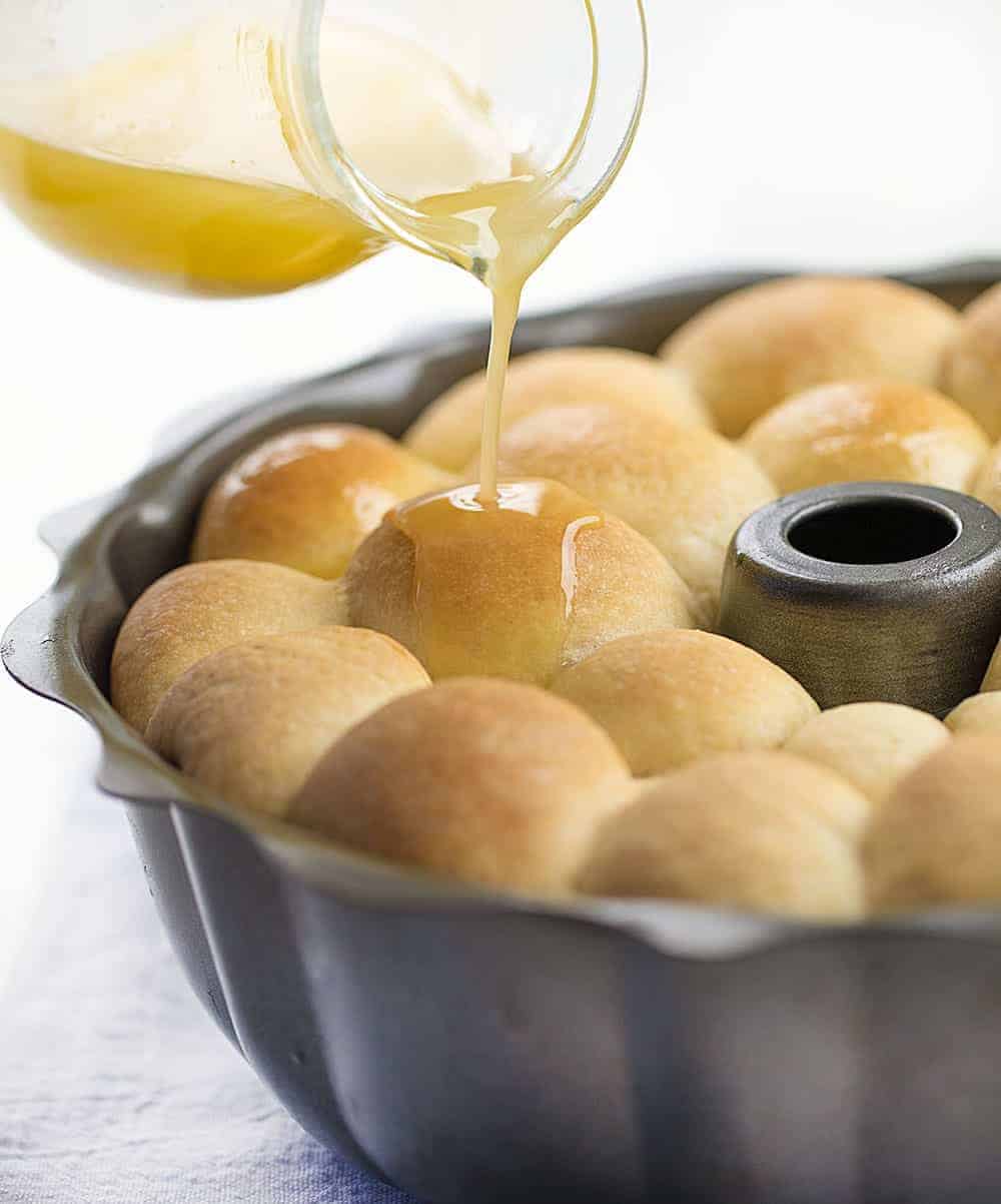Buttery Bubble Bread is homemade bread that is a soft, salty, and buttery pull-apart bread that is easy to make and perfect for dinner rolls! Butter Bread, Bubble Bread, Buttery Bubble Bread, Bundt Bread, Dinner Rolls, Thanksgiving, Christmas rolls, bread recipe, homemade bread, rolls, i am baker, iambaker, recipes 在烤盘里把黄油浇在泡沫面包上