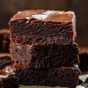 三双巧克力布朗尼互相堆叠在一个黑暗的砧板。