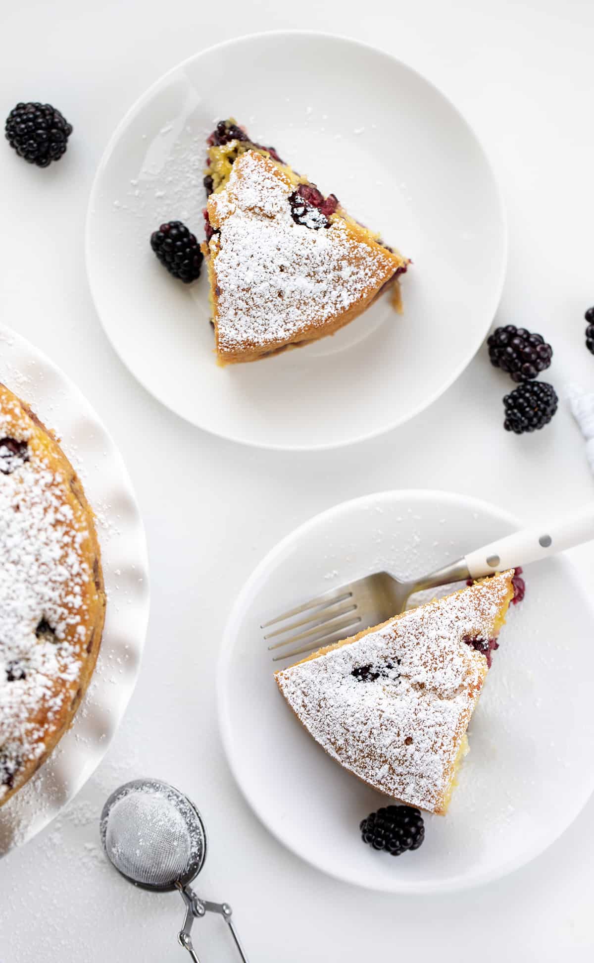 白与黑莓的早餐蛋糕盘子用白色的形式和新鲜黑莓在白色的计数器。
