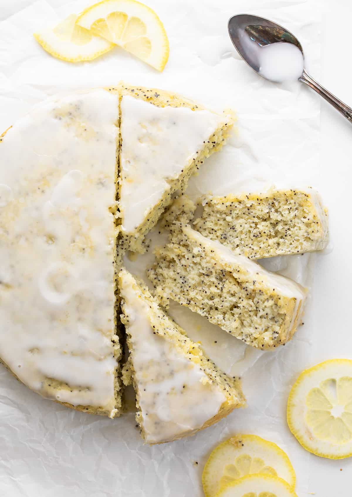 整个柠檬罂粟籽蛋糕一块白色的羊皮纸上四块,两块显示温柔的碎屑。