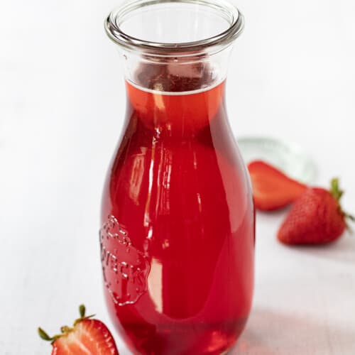 一瓶草莓简单糖浆草莓包围。