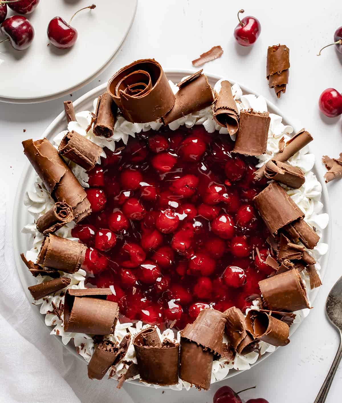 黑森林芝士蛋糕在白色的表面从开销和一些白色的盘子和樱桃。