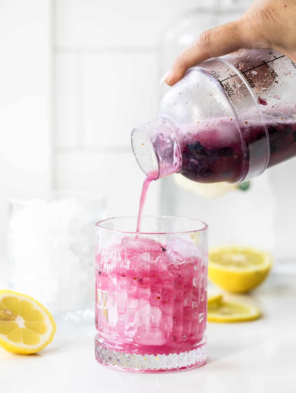注入新鲜动摇飙升蓝莓柠檬水从瓶玻璃与冰白色柜台柠檬。