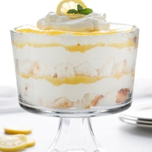 柠檬奶油蛋糕在白色柜台玻璃蛋糕盘与柠檬和盘子。