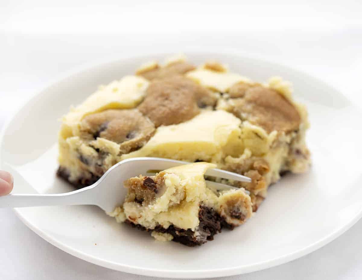 叉子咬了一口白色盘子里的巧克力饼干芝士蛋糕