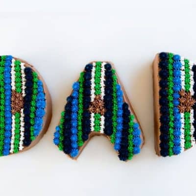 字母D, A, D，从蛋糕上剪下来，配上蓝色和绿色的奶油。