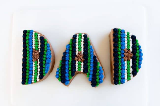 字母D, A, D，从蛋糕上剪下来，配上蓝色和绿色的奶油。