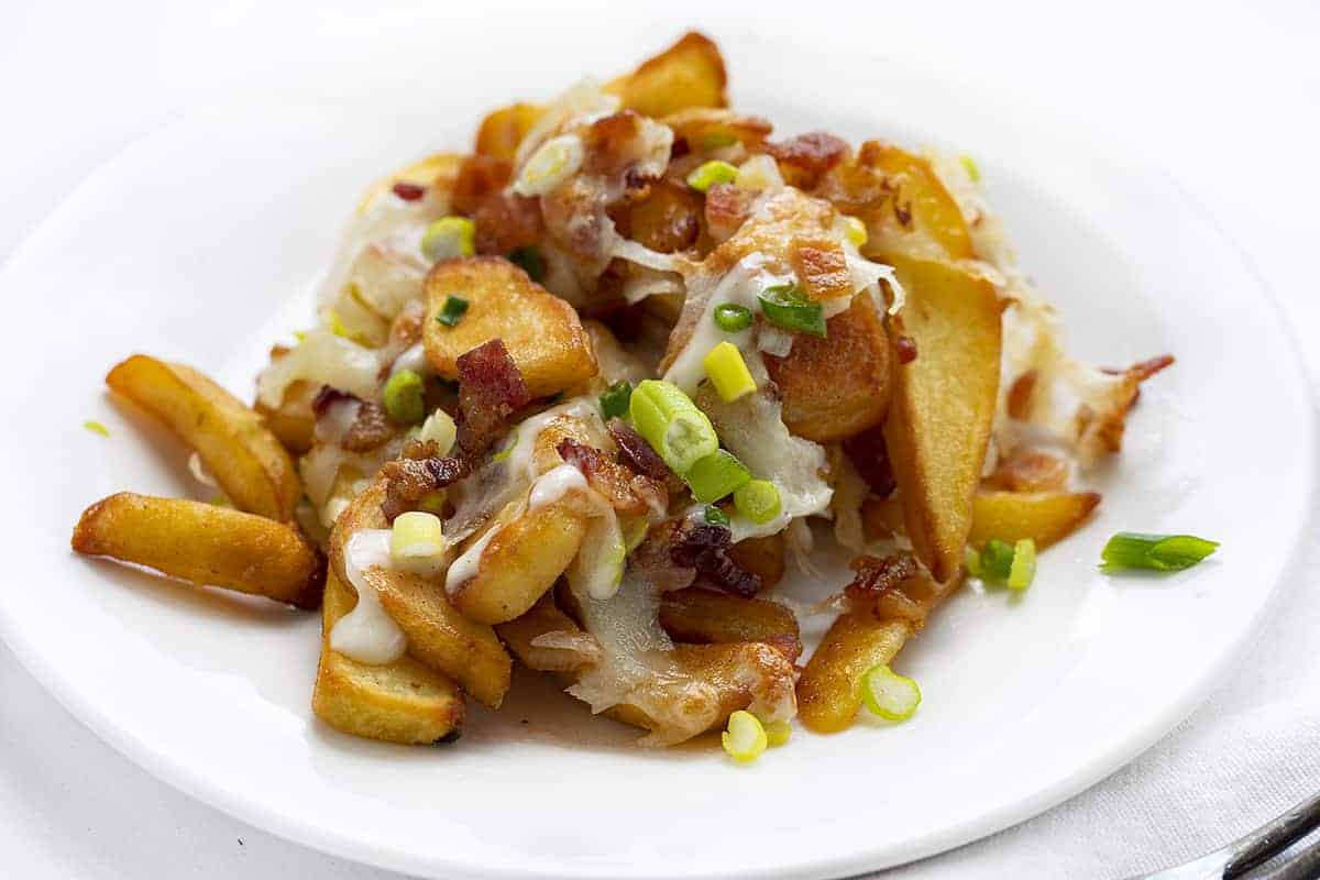 盘芝士薯条顶部有熏肉,奶酪,和葱