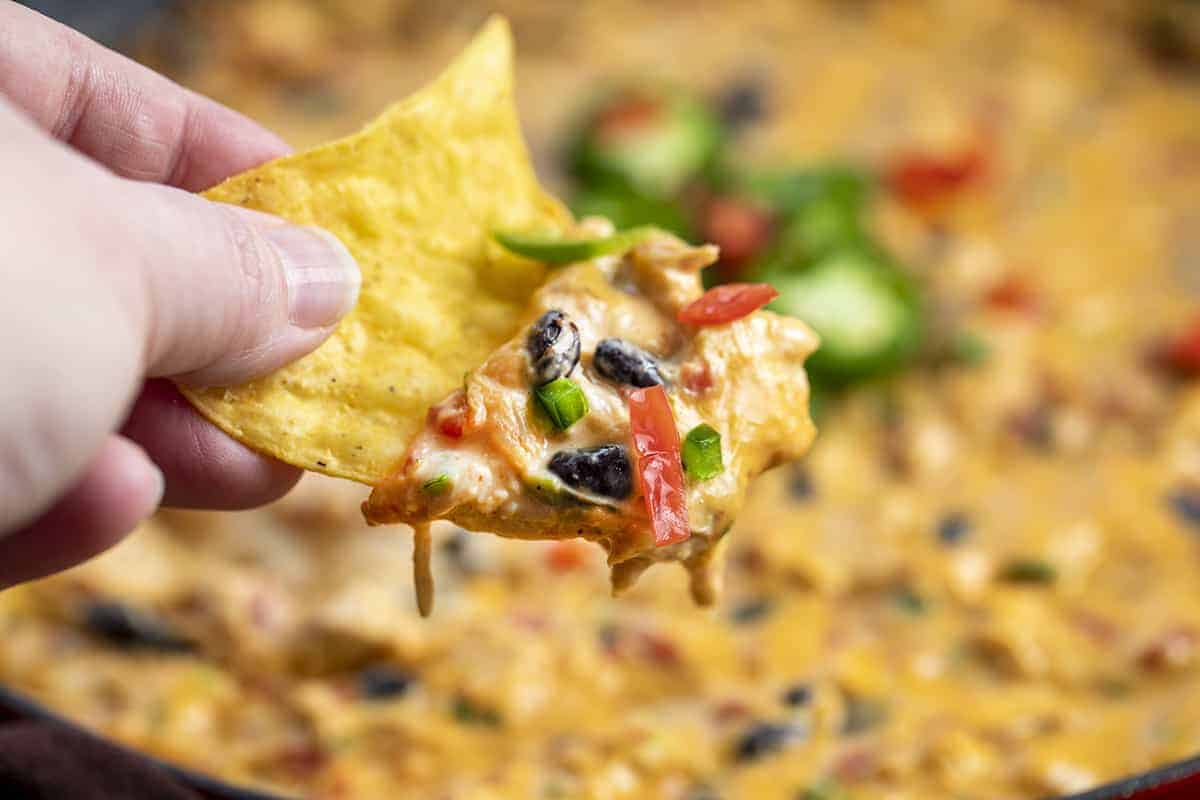 手拿一块鸡肉薯条，上面蘸着Velveeta奶酪