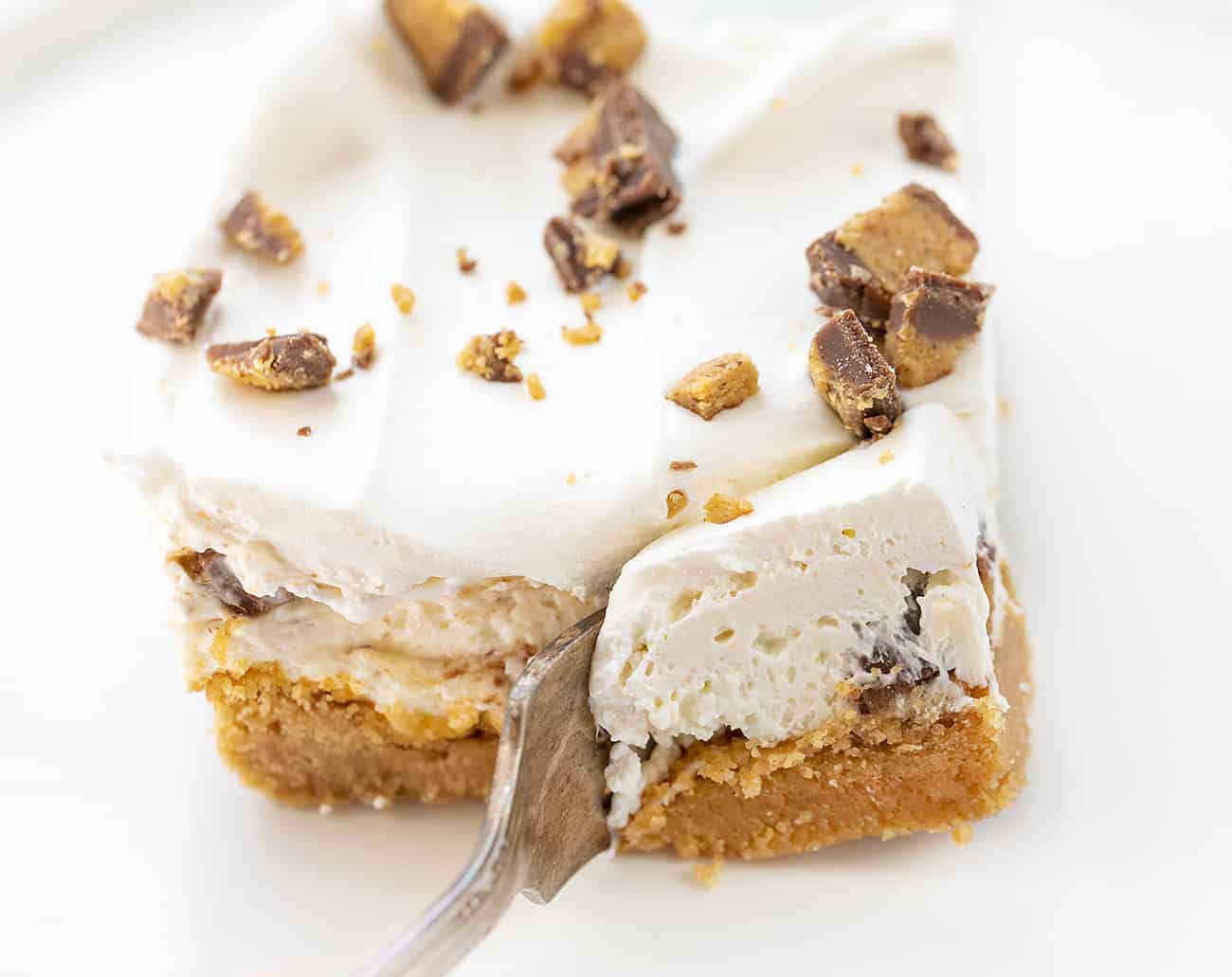 Fork Cutting into Reeses Peanut Butter Bar on White Plate