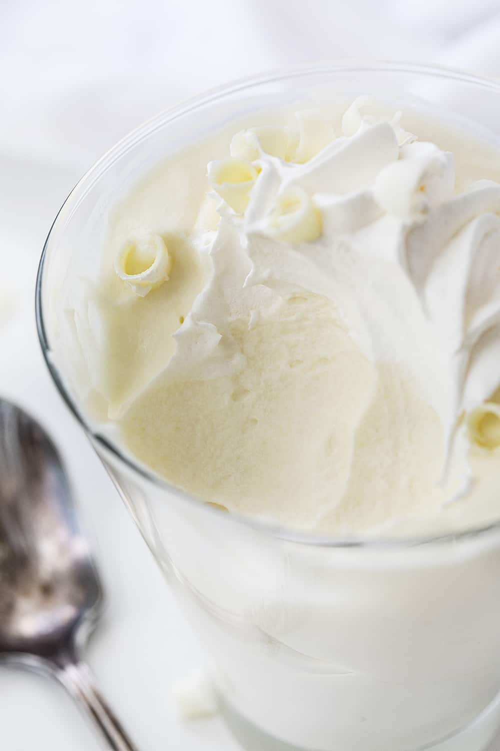 一杯白巧克力慕斯移除和勺子旁边玻璃