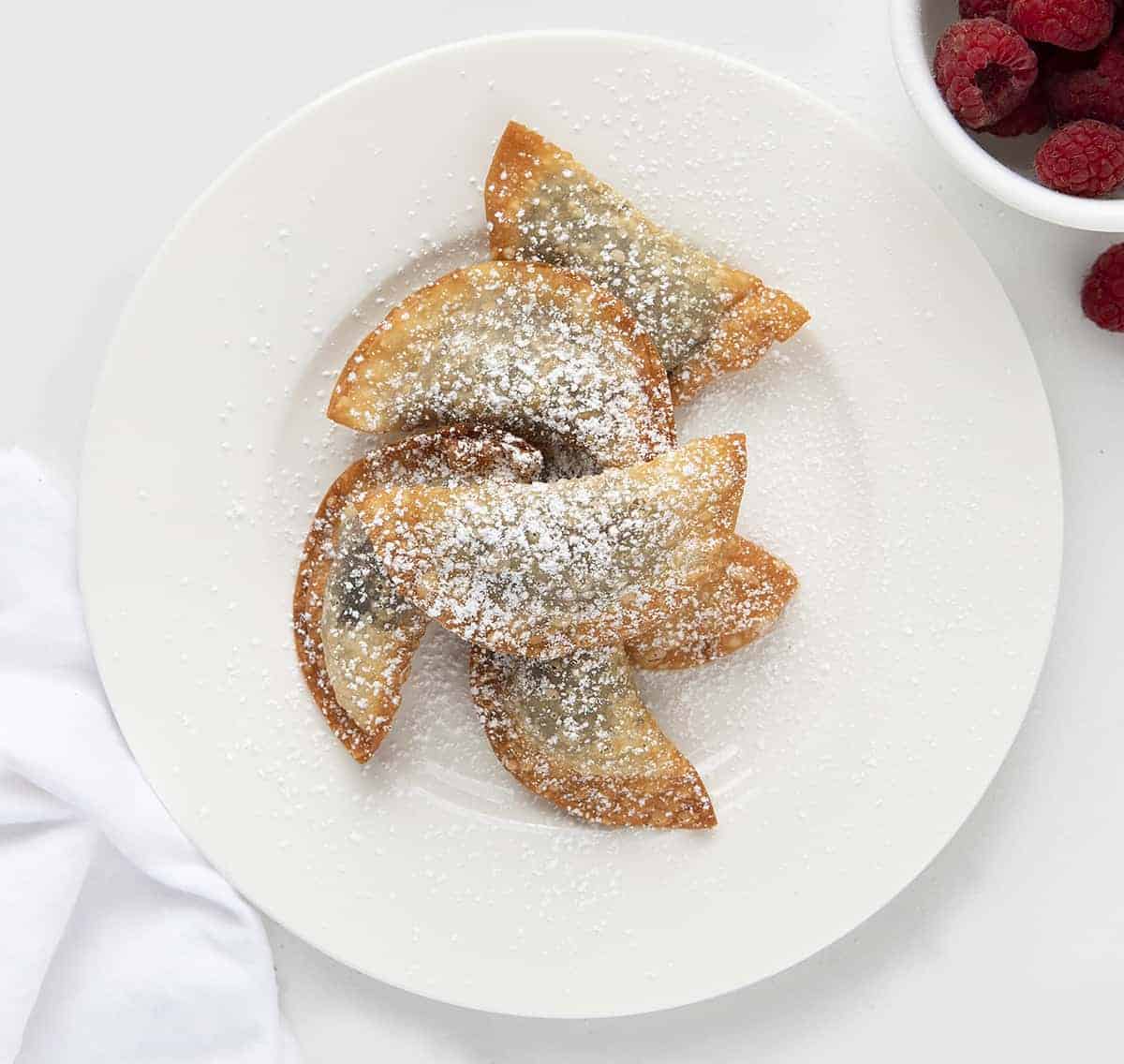 油炸奥利奥馄饨放在白色盘子里，后面放覆盆子