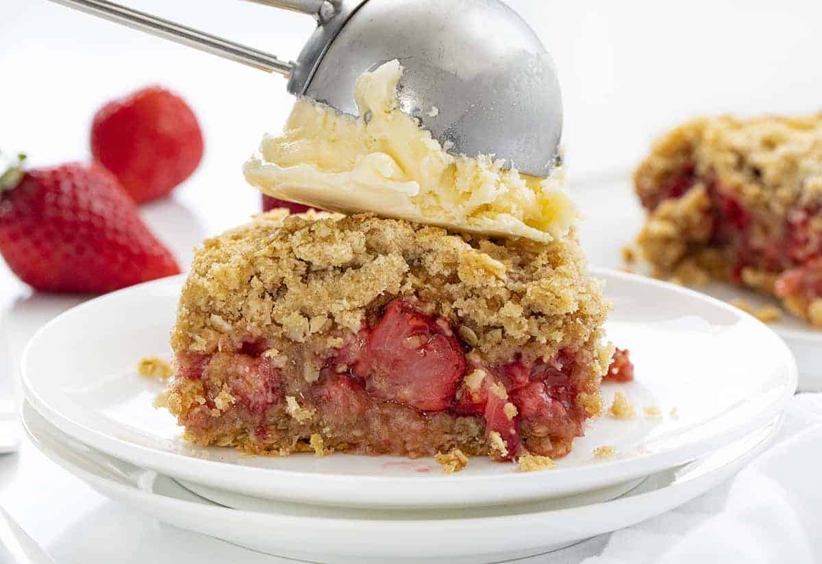 添加一勺冰激凌,草莓脆在两个白色的盘子gydF4y2Ba