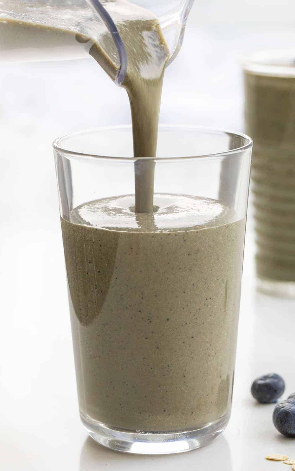 把蓝莓菠菜早餐奶昔倒进杯子里