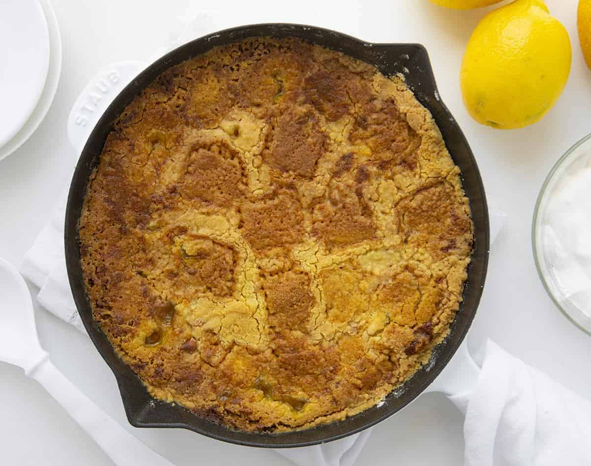 头顶图像柠檬奶油奶酪倾倒蛋糕在白色煎锅柠檬和器皿周围