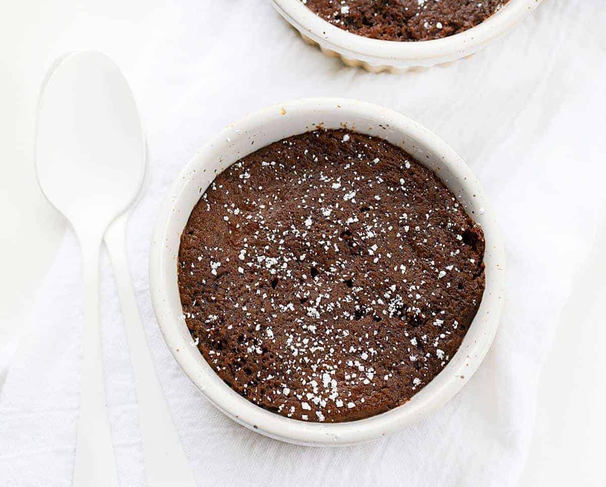 巧克力糖浆马克杯蛋糕在白色毛巾和白色勺子的俯视图