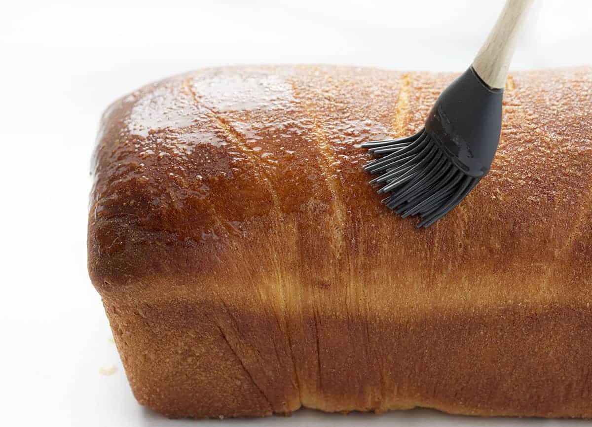 在烘烤的自制肉桂葡萄干面包上刷黄油