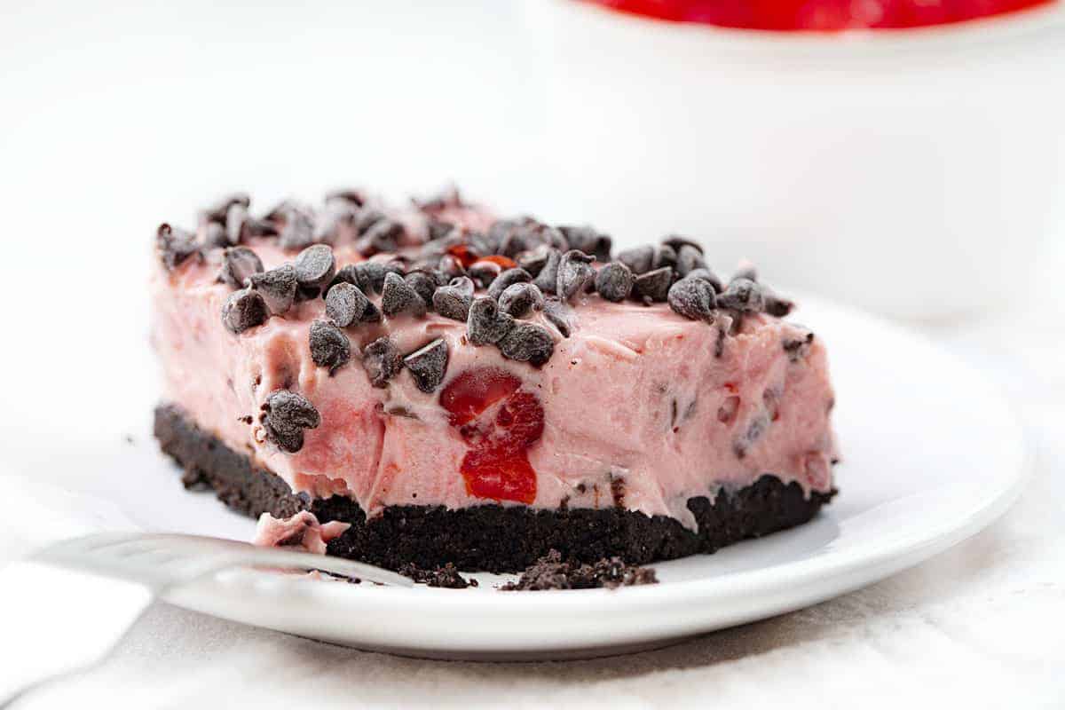 从白色盘子上的巧克力樱桃棒上咬下一口