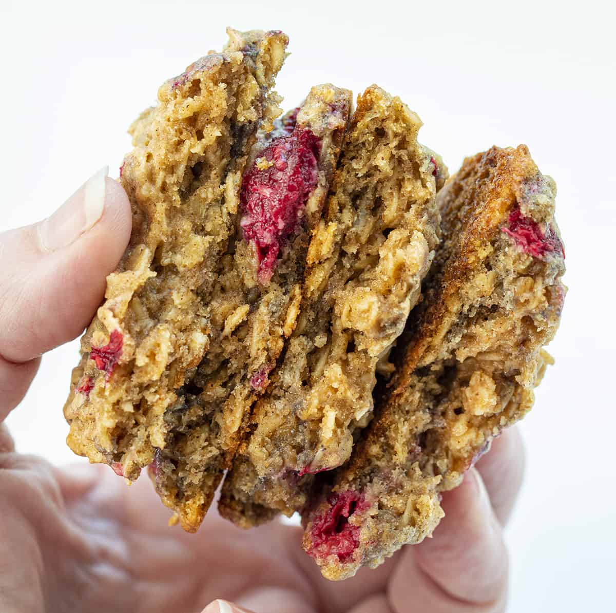 手握碎成两半的覆盆子燕麦饼干显示里面的纹理。饼干，烘焙，覆盆子饼干，覆盆子燕麦饼干，饼干食谱，饼干交换，水果饼干，夏天烘焙，更健康的饼干食谱，甜点，我是面包师，iambaker