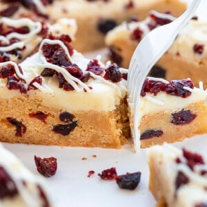 叉子咬了一口蔓越莓极乐棒，展示了棒的柔软质地和奶油奶酪糖霜。