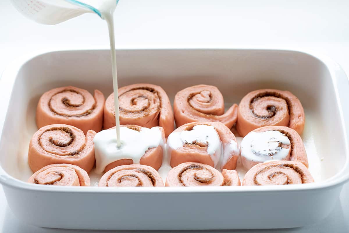 在粉色肉桂卷上倒浓奶油。