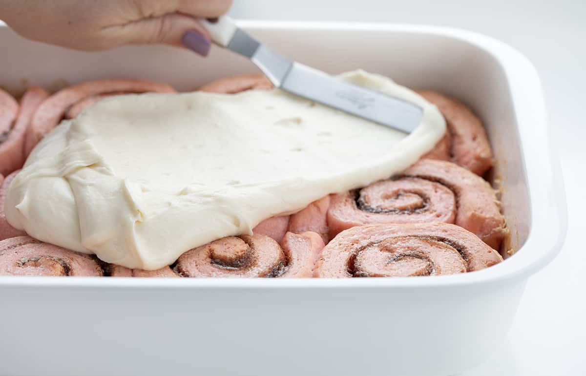 在粉色肉桂卷上撒糖霜。