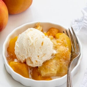 一碗桃松饼烤白色柜台桃子和叉子和一勺香草冰淇淋。
